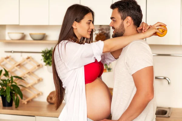 Pareja embarazada de pie en su cocina preparando — Foto de Stock