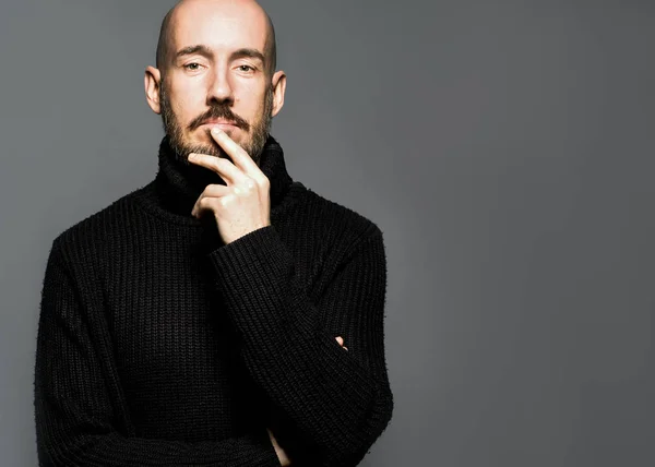 Fashion Portrait of a 40-year-old man standing over a light gray background in a black sweater. Close up. Classic style. Bald shaved head. Copy-space. Studio shot — Stock Photo, Image