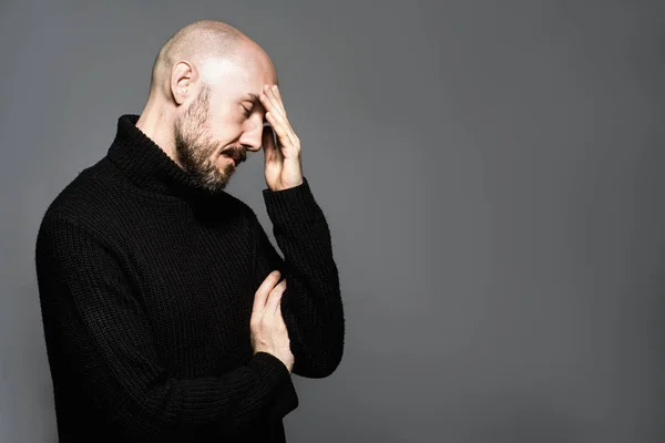 Modeportret van een 40-jarige man die in een zwarte trui over een lichtgrijze achtergrond staat. Sluit maar af. Klassieke stijl. Kaal geschoren hoofd. Begrepen-ruimte. Studioshoot — Stockfoto