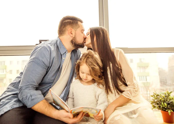 Glückliche Familie, die ihrer Tochter ein Buch vorliest. Muttertag. — Stockfoto