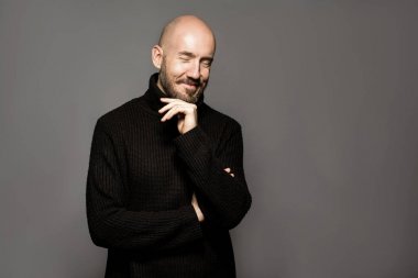 Moda portre siyah kazak bir ışık gri arka plan üzerinde ayakta adam. Yakın çekim. Klasik tarzı. Kel kafası tıraşlı. Boşluk. Stüdyo vurdu