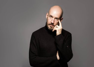 Moda portre siyah kazak bir ışık gri arka plan üzerinde ayakta adam. Yakın çekim. Klasik tarzı. Kel kafası tıraşlı. Boşluk. Stüdyo vurdu