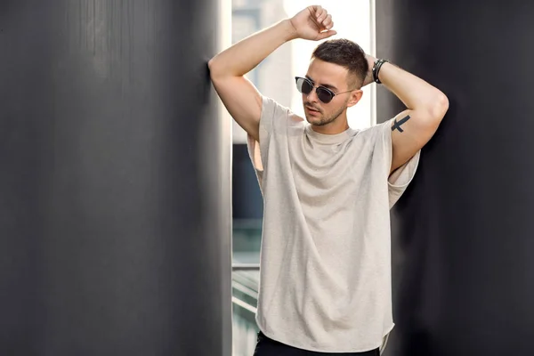Un tipo alla hipster. Uomo di moda in piedi vicino al muro nero — Foto Stock
