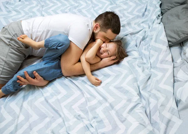 Táta a dcera bavit doma na posteli. Den otců. — Stock fotografie