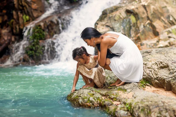 Madre feliz con su hija en los trópicos cerca de la cascada. Día de las madres . — Foto de Stock