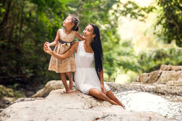 Mãe feliz com sua filha nos trópicos perto da cachoeira. Dia das mães . — Fotografia de Stock