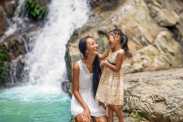 Madre feliz con su hija en los trópicos cerca de la cascada. Día de las madres . — Foto de Stock