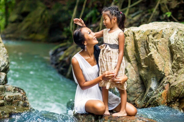 asian happy mother with her daughter in the tropics near the watterfall. Mothers day.