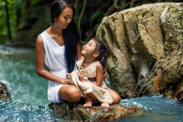 Asiática mãe feliz com sua filha nos trópicos perto da cachoeira. Dia das mães . — Fotografia de Stock