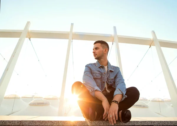 Fashion guy sitting at sunset posing — Stock Photo, Image