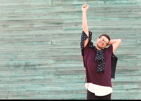 Moda ragazzo in occhiali posa vicino a un muro di legno in blu — Foto Stock