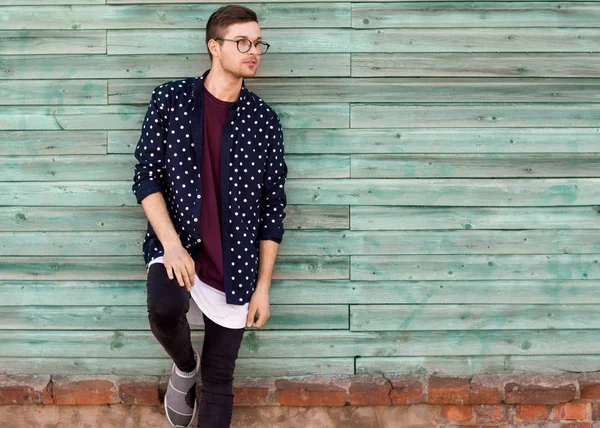 Moda chico hipster en gafas de moda posando sobre un fondo azul de madera —  Fotos de Stock