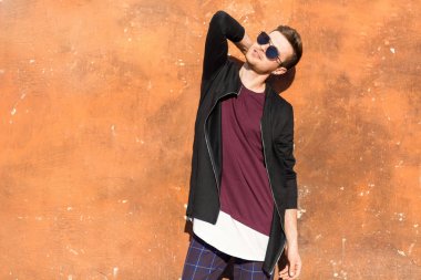 kırık boya buruşuk bir beton duvarla yakınındaki gözlüklü adam moda standları