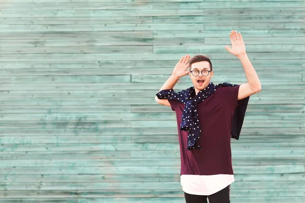 Moda ragazzo in occhiali posa vicino a un muro di legno in blu — Foto Stock