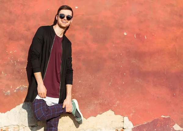 Mode killen i glasögon står nära en skrynkligt betongvägg med sprucken färg — Stockfoto