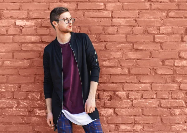 bir tuğla duvar kırık boya ile yakınındaki gözlüklü adam moda standları