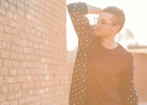 Modemann mit Brille steht neben einer Ziegelwand mit rissiger Farbe — Stockfoto