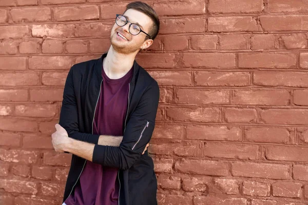 Mode kerel in glazen staat in de buurt van een bakstenen muur met gebarsten verf — Stockfoto