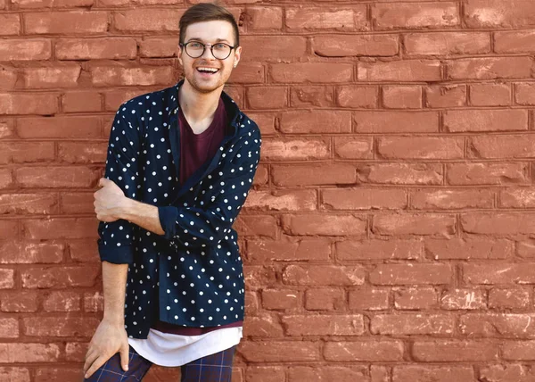 Mode kerel in glazen staat in de buurt van een bakstenen muur met gebarsten verf — Stockfoto