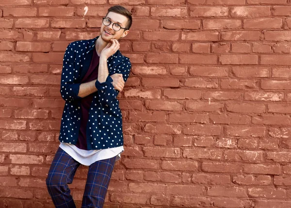 Modemann mit Brille steht neben einer Ziegelwand mit rissiger Farbe — Stockfoto