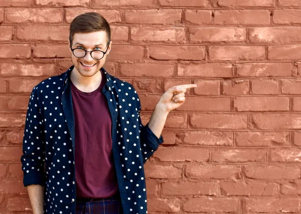 Mode kerel in glazen staat in de buurt van een bakstenen muur met gebarsten verf — Stockfoto