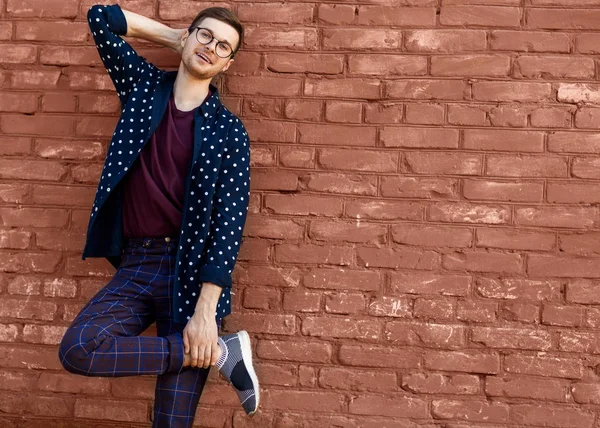 bir tuğla duvar kırık boya ile yakınındaki gözlüklü adam moda standları