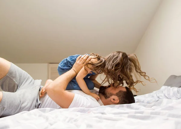 Dad and daughter have fun at home on the bed. Father\'s Day.