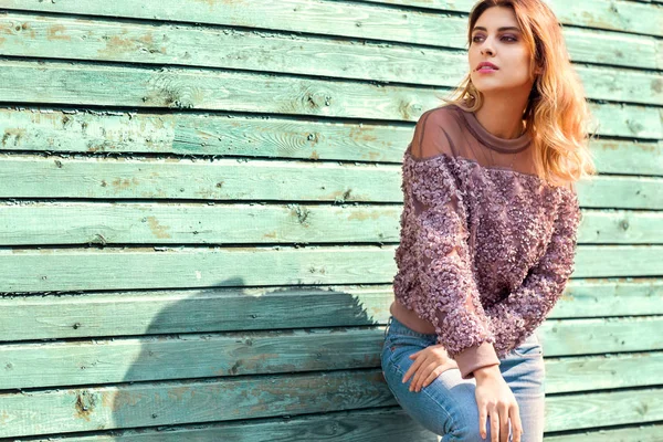 Mode flicka poserar nära en turkos trävägg — Stockfoto