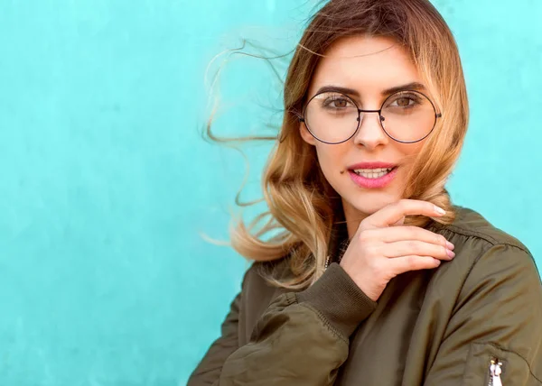 Mode flicka i runda glasögon står posing nära en turkos wal — Stockfoto