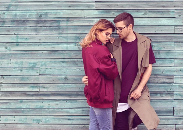 Mode paar in hun bril met donkerrood kleren poseren op een blauwe houten muur — Stockfoto