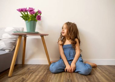 küçük kız evde yatak oynamaya yakın oturan