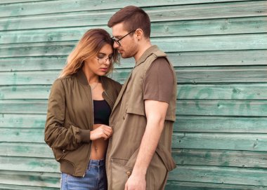 moda çift ayakta yeşil ahşap duvara yakın poz