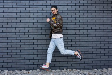 Şehir merkezinde siyah tuğlalı bir duvarda poz veren moda adamı.
