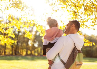 father with daughter walks in the autumn park happy at sunset