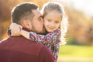 Baba ve kızı gün batımında parkta oynuyorlar.
