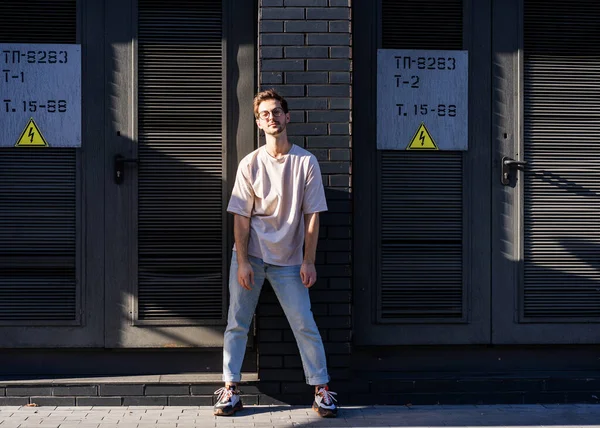 Ragazzo di moda in posa su un muro di mattoni neri in un quartiere urbano — Foto Stock