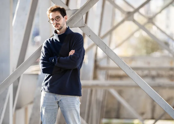 Fashion guy stands posing near a black brick wall in sunglasses — Stock Photo, Image