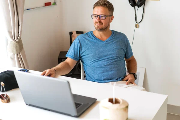 Freelancer cara está sentado no escritório trabalhando e bebendo coco — Fotografia de Stock