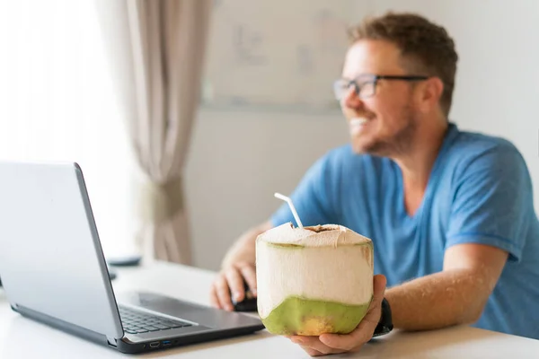 Freelancer cara está sentado no escritório trabalhando e bebendo coco — Fotografia de Stock