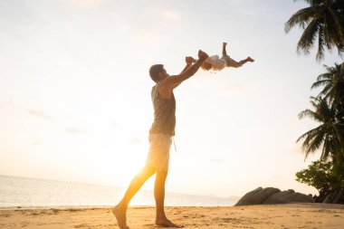 dad with a child at sunset on the beach having fun and spinning
