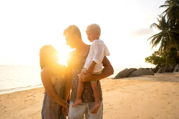 Famille se promène joyeusement le long d'une plage tropicale au coucher du soleil — Photo