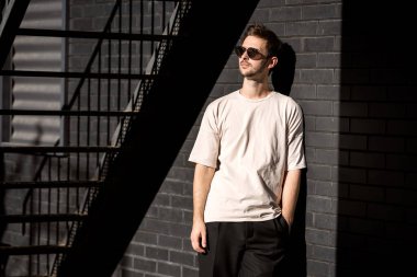 Siyah bir şehir geçmişine karşı güneş gözlüğü takan modacı.