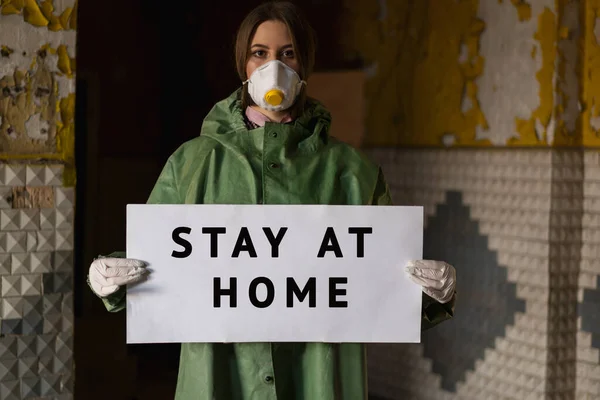 stock image Doctor wearing protection face mask against coronavirus. Staff preventive gear. Holding a poster stay at home in hands