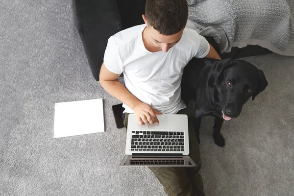 freelancer guy with laptop and dog is working at home in quarantine to coronavirus infection