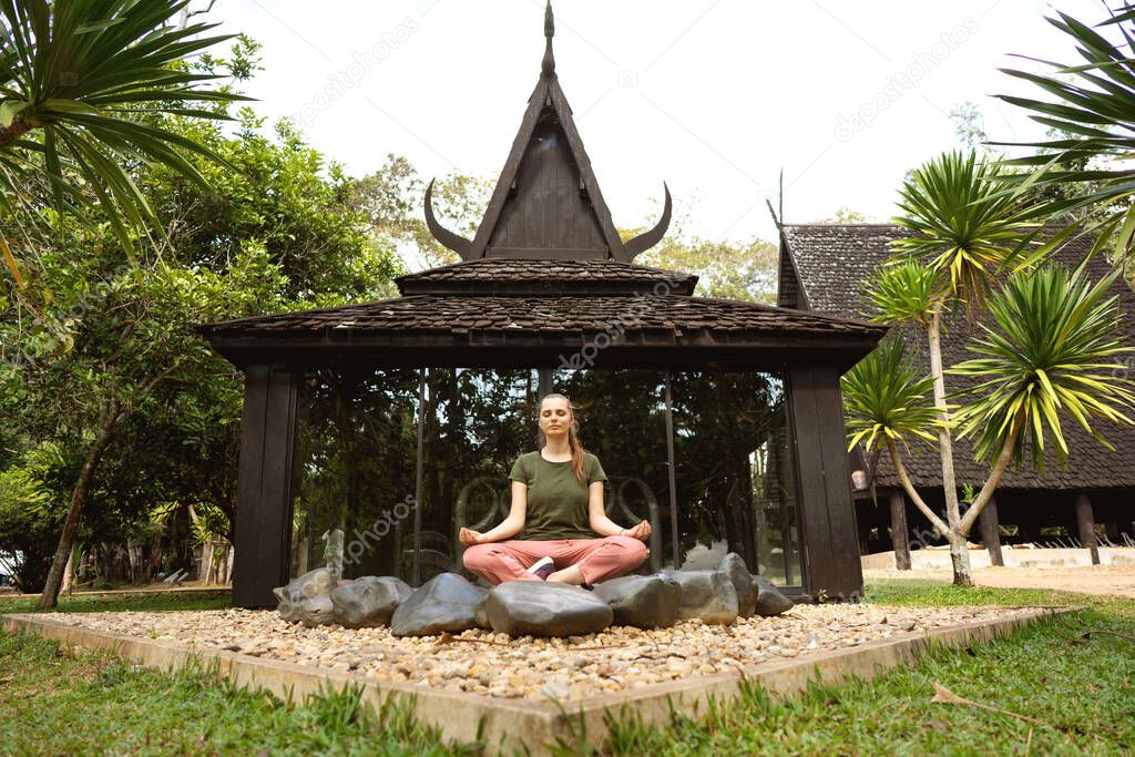 girl meditates on the background of a beautiful temple in Thailand