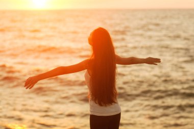 Özgür kadın gün batımında kumsalda mutlu olmanın tadını çıkarıyor. Saf mutlulukta huzur veren güzel bir kadın ve kollarını açmış keyifle eğlenen bir kadın. Asyalı Kafkas kadın modeli.