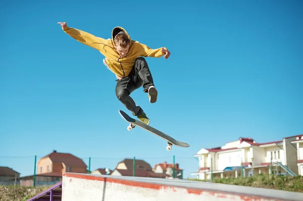 En teenager skateboarder gør et flip trick i en skatepark i udkanten af byen - Stock-foto