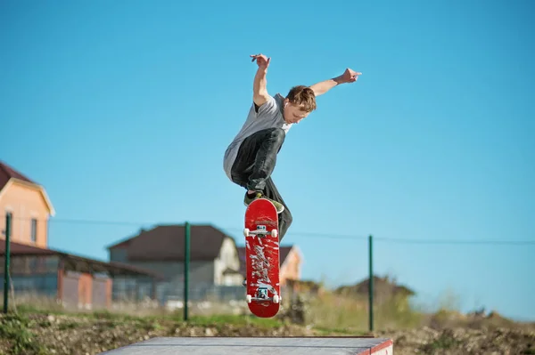 Egy tinédzser gördeszkás csinál egy ollie trükk egy skatepark, a város szélén — Stock Fotó