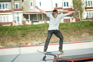 Genç bir adam bir kılavuzda bir kaykay üzerinde bir skatepark evin arka plan üzerinde slaytlar