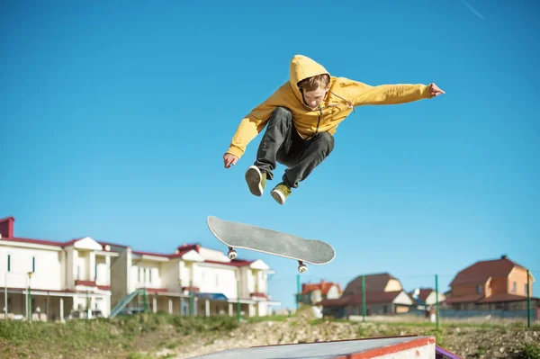 Een tiener skateboarder doet een flip truc in een skatepark aan de rand van de stad — Stockfoto